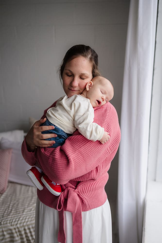 mom snuggles sleeping baby during valentine's themed 3 month milestone photography session in knoxville tn