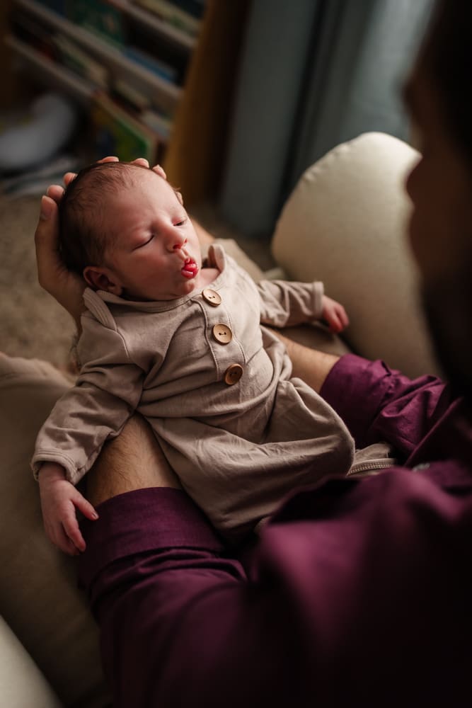 newborn sticking tongue out at dad during in home lifestyle newborn photography session in knoxville tn