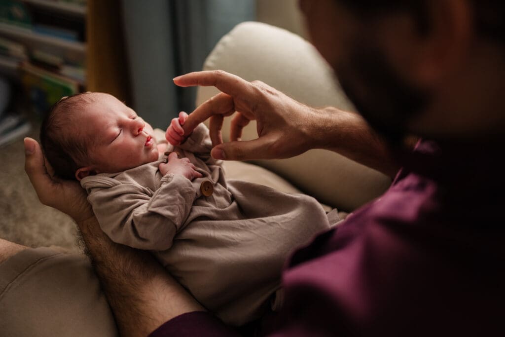 baby boy grips dad's finger during in home lifestyle newborn photography session in knoxville tn