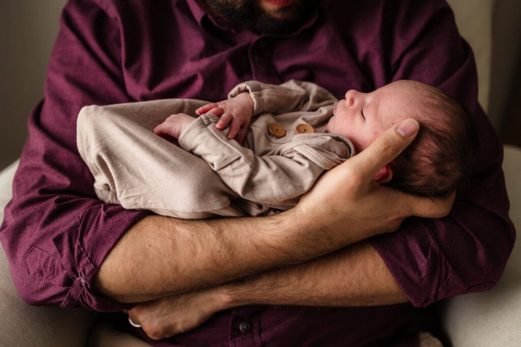 newborn in dad's arms during in home lifestyle newborn photography session in knoxville tn