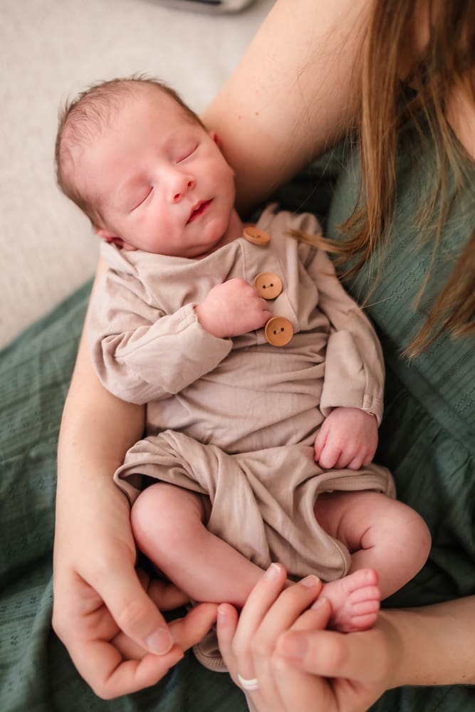 baby boy snuggled in moms arms during in home lifestyle newborn photography session in knoxville tn