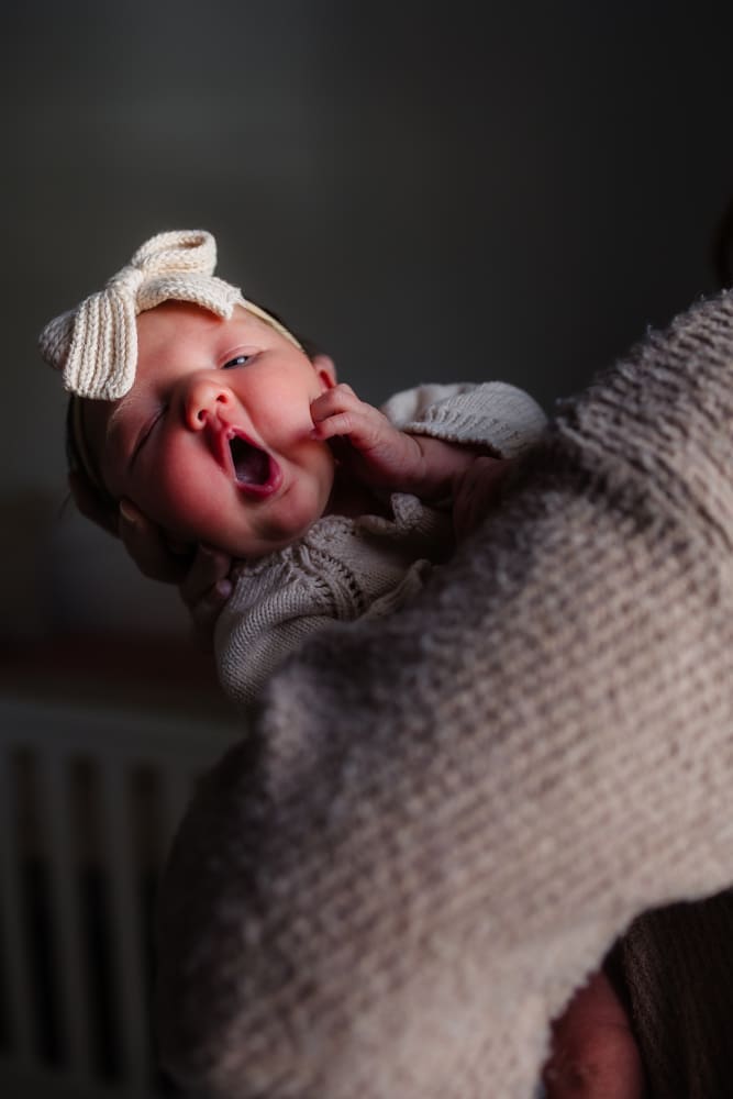 baby yawning in moms arms during in-home lifestyle newborn session by knoxville newborn and maternity photographer Kelsey Wood Portraits.