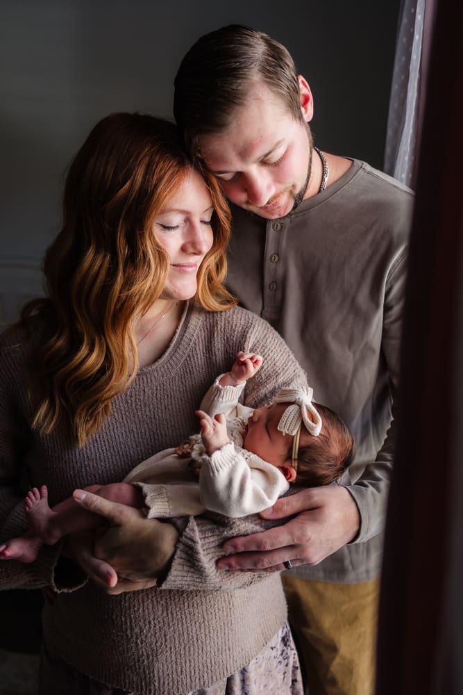 mom and dad snuggle newborn during in-home lifestyle newborn session by knoxville newborn and maternity photographer Kelsey Wood Portraits.