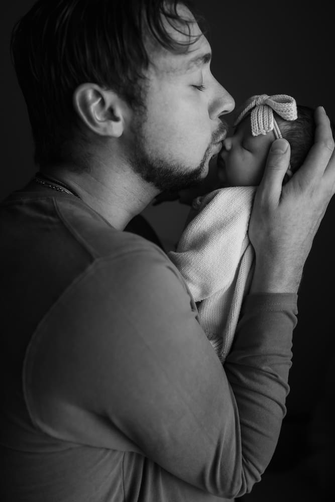 dad kissing newborn during in-home lifestyle newborn session by knoxville newborn and maternity photographer Kelsey Wood Portraits.