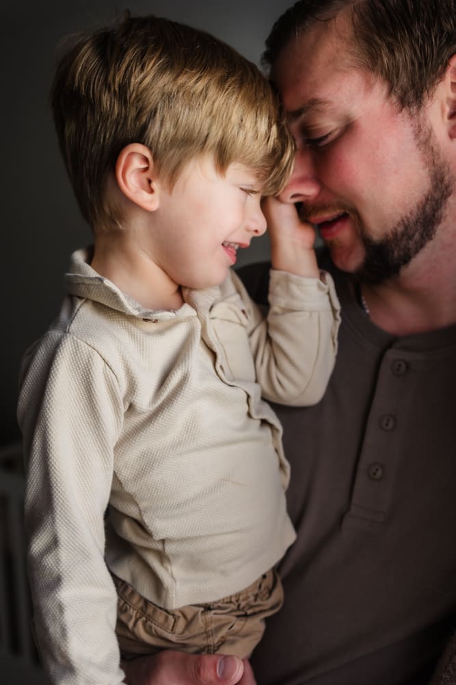 dad snuggles older son during in-home lifestyle newborn session by knoxville newborn and maternity photographer Kelsey Wood Portraits.