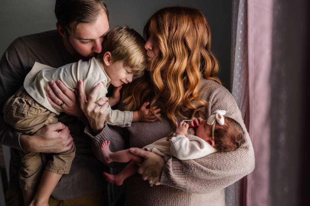 family by window during in-home lifestyle newborn session by knoxville newborn and maternity photographer Kelsey Wood Portraits.