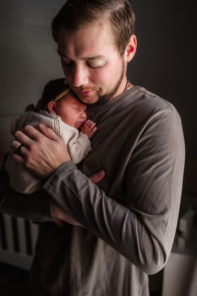 dad snuggles newborn on his chest during in-home lifestyle newborn session by knoxville newborn and maternity photographer Kelsey Wood Portraits.