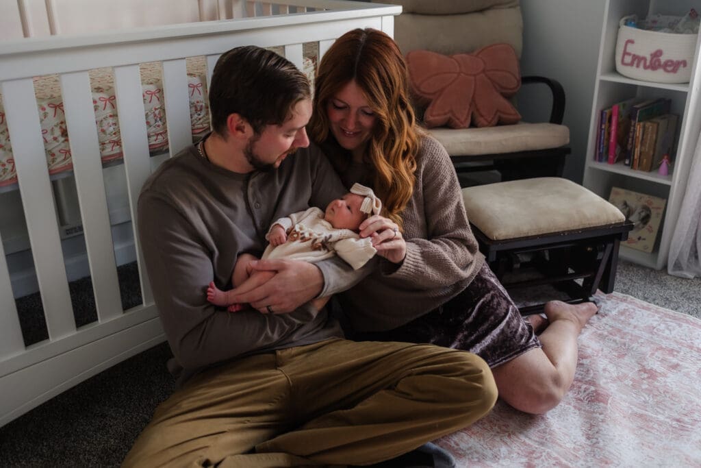 mom and dad on the floor of the nursery during in-home lifestyle newborn session by knoxville newborn and maternity photographer Kelsey Wood Portraits.