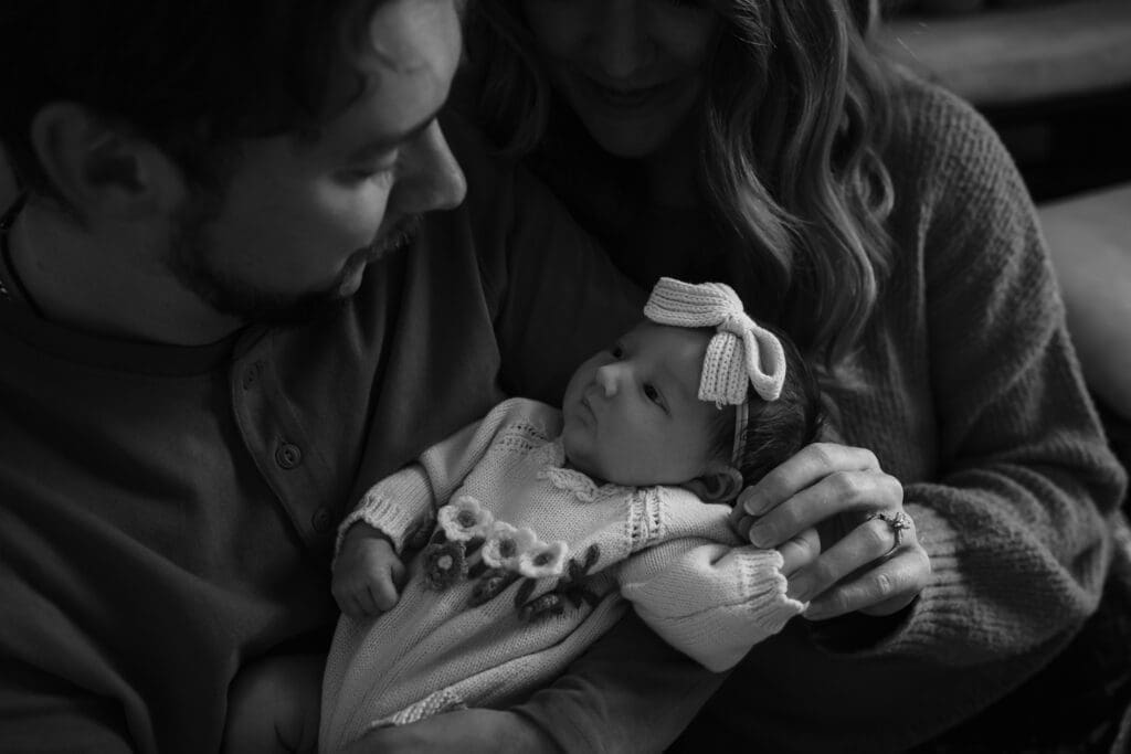 mom and dad snuggling newborn during in-home lifestyle newborn session by knoxville newborn and maternity photographer Kelsey Wood Portraits.