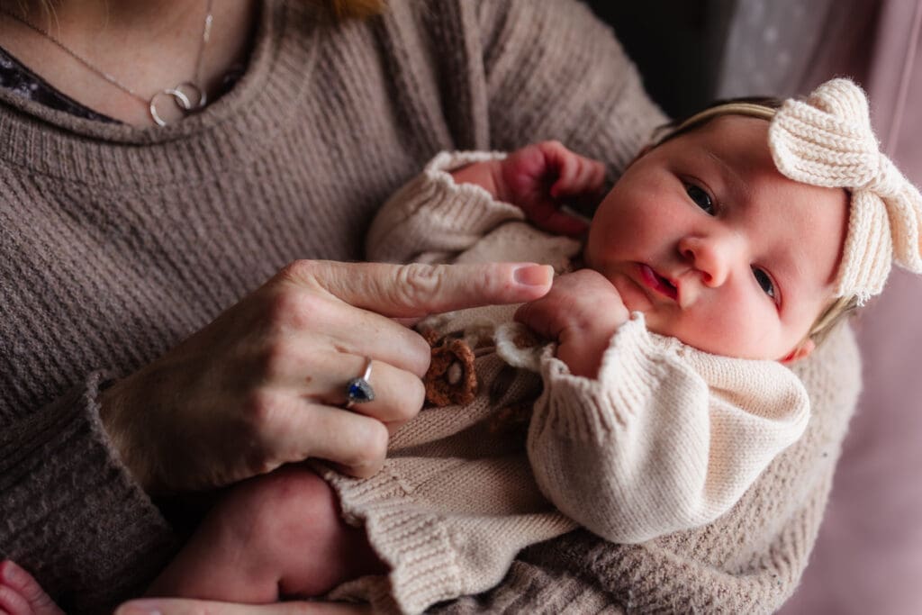 mom holding baby during in-home lifestyle newborn session by knoxville newborn and maternity photographer Kelsey Wood Portraits.