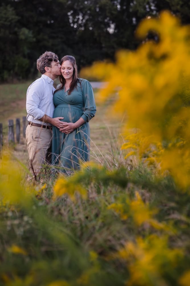 dad kissing mom during knoxville maternity photo shoot at seven isalnds park in kodak