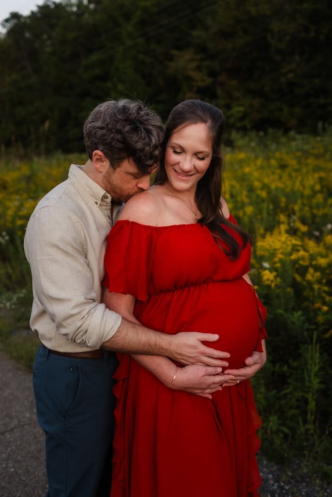 dad kissing mom's shoulder during knoxville maternity photo shoot at seven isalnds park in kodak