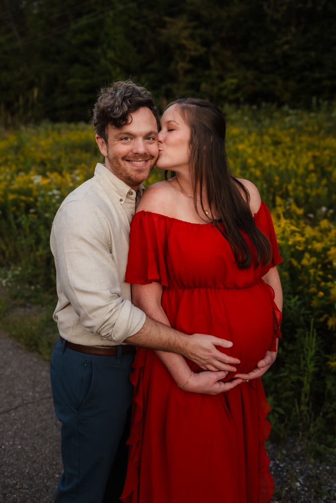 mom kissing dad on the cheek during knoxville maternity photo shoot at seven isalnds park in kodak