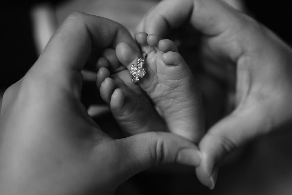 wedding ring on baby toes with moms hands in a heart during in-home lifestyle newborn photography session in knoxville tn