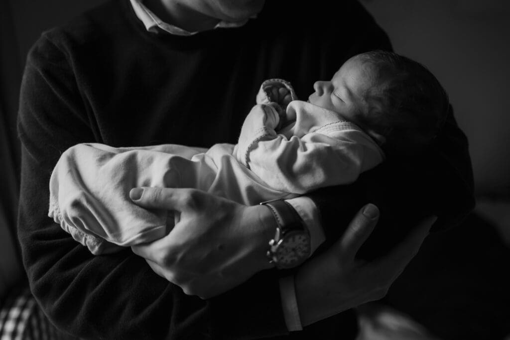 newborn in dads arms during in-home lifestyle newborn photography session in knoxville tn