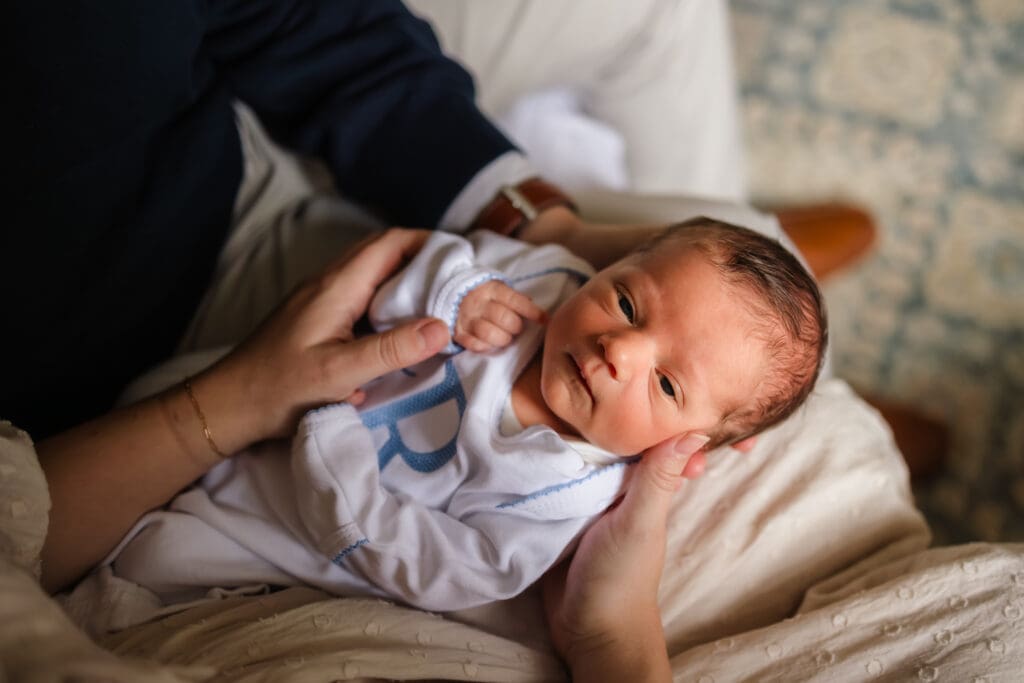 baby looking at camera on mom and dads lap during in-home lifestyle newborn photography session in knoxville tn