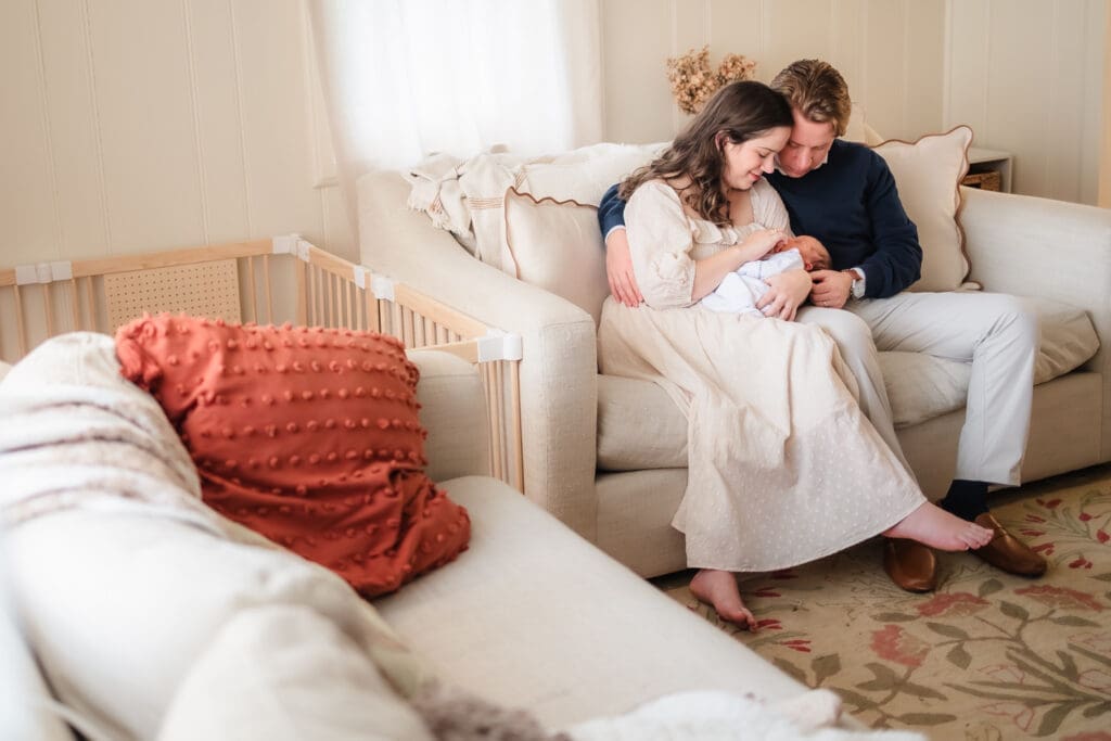 mom and dad admire newborn on the couch during in-home lifestyle newborn photography session in knoxville tn