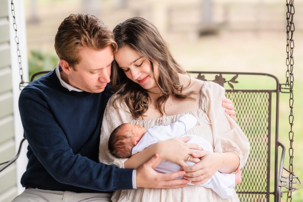 mom and dad on porch swing during in-home lifestyle newborn photography session in knoxville tn