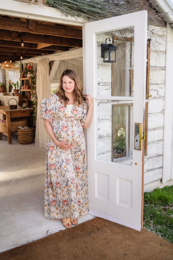 expecting mama leans against the doorway of the glassholm studio during knoxville maternity photography session at the Holmstead studio