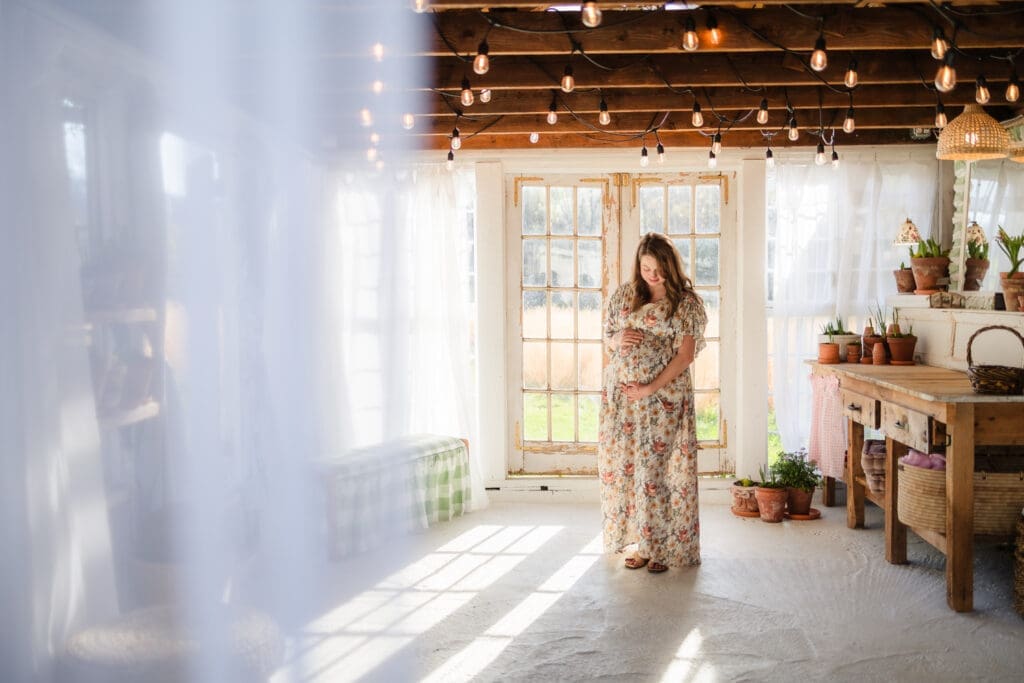 expecting mama holding baby bump during knoxville maternity photography session at the Holmstead studio