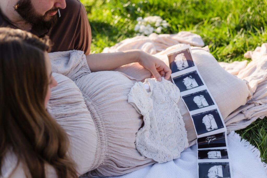 mom and dad looking at onesie and ultrasound pregnancy announcement style during knoxville maternity photography session at the Holmstead studio