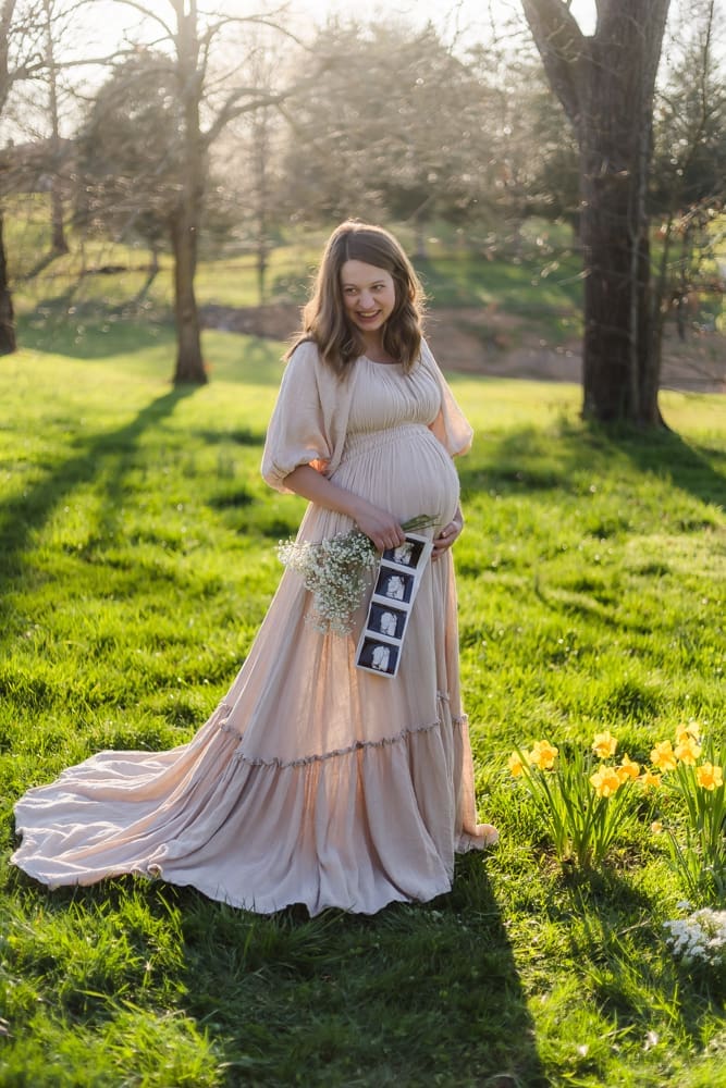 mom laughing and holding ultrasound and babys breath during knoxville maternity photography session at the Holmstead studio