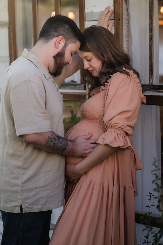 mom and dad looking at baby bump during knoxville maternity photography session at the Holmstead studio