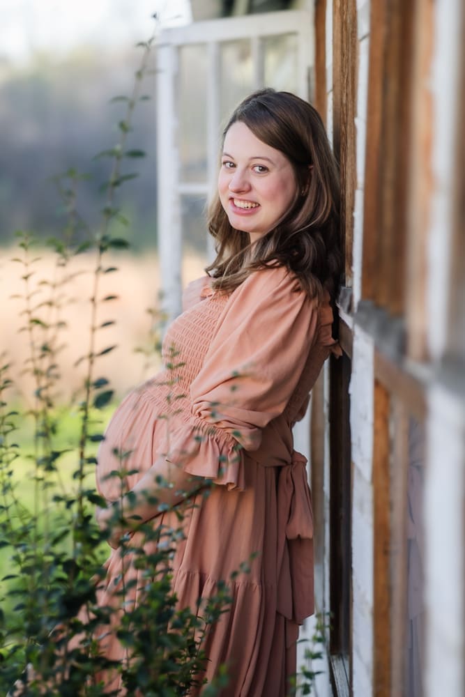 mom leaning against wall during knoxville maternity photography session at the Holmstead studio