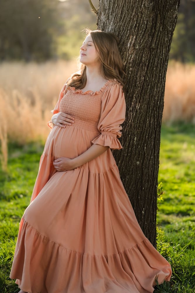 mom leaning against tree during knoxville maternity photography session at the Holmstead studio