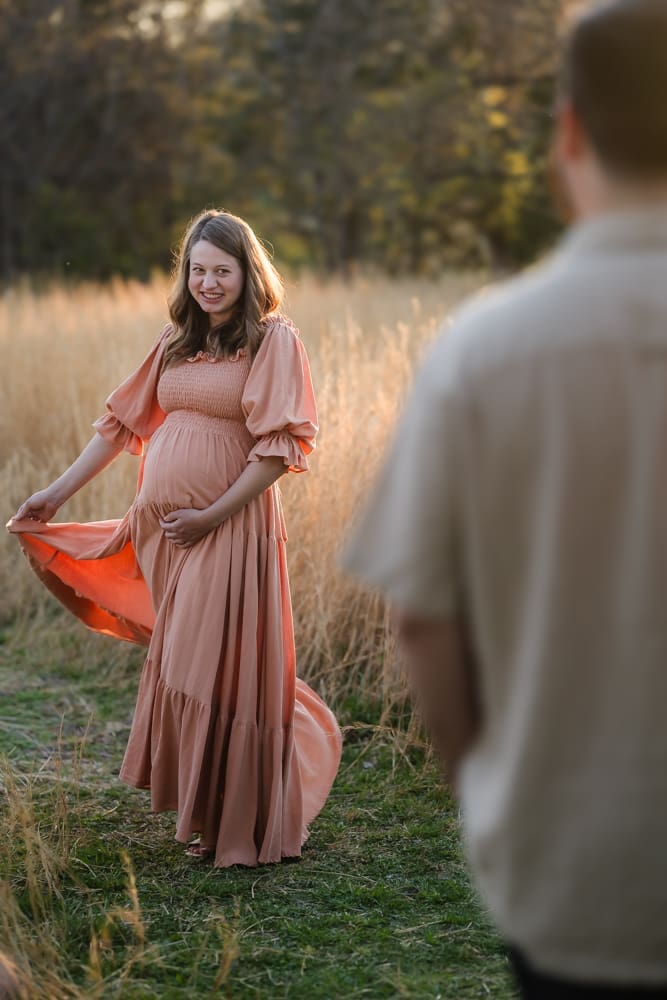 mom twirling dress and looking at dad during knoxville maternity photography session at the Holmstead studio