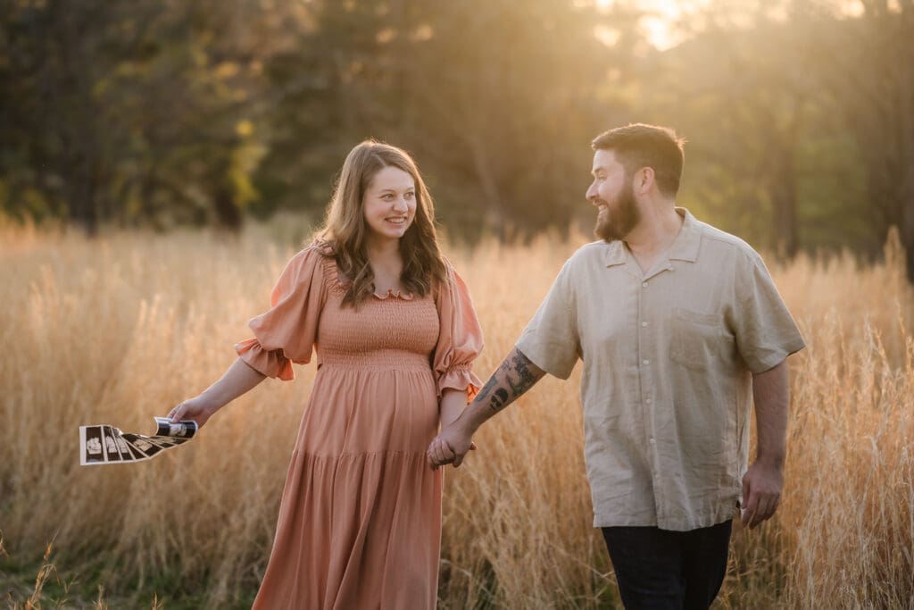 mom and dad walking with ultrasound  pregnancy announcement style during knoxville maternity photography session at the Holmstead studio