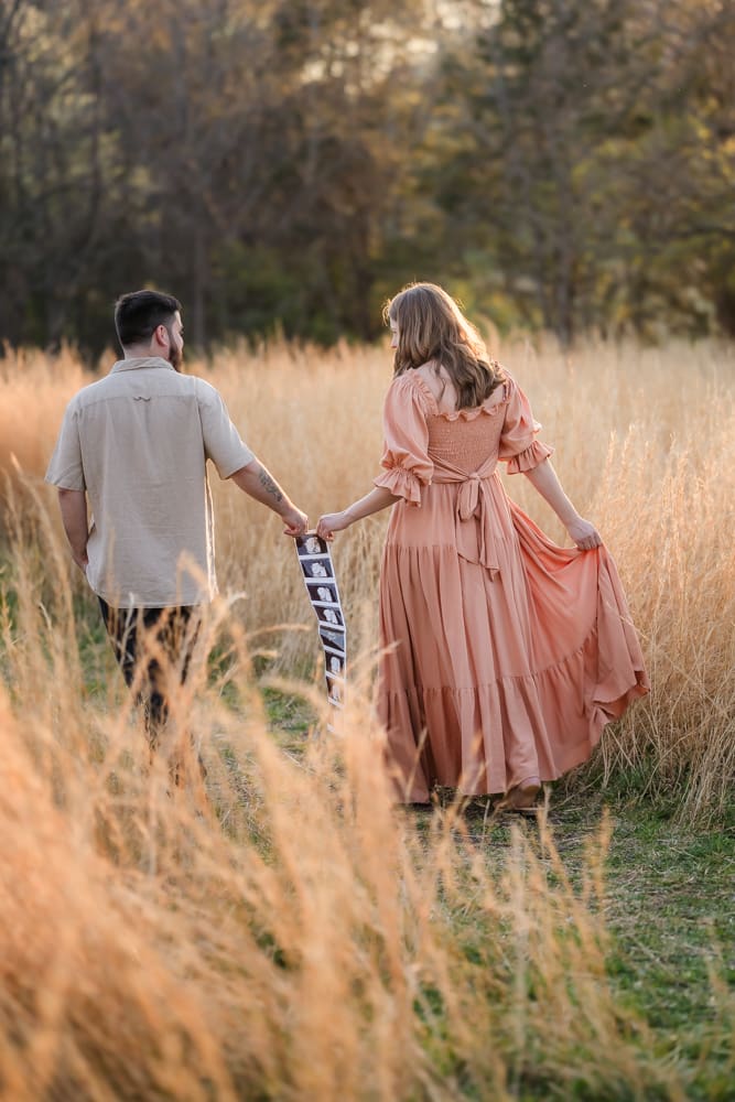 mom and dad walking away with pregnancy anouncement during knoxville maternity photography session at the Holmstead studio