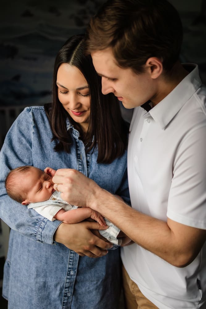 mom and dad admiring newborn baby boy during knoxville in-home lifestyle newborn photography session