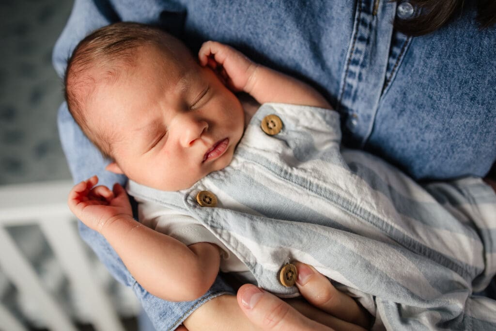 baby sleeping with arms up in moms arms during knoxville in-home lifestyle newborn photography session