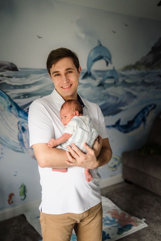 dad holding newborn son during knoxville in-home lifestyle newborn photography session