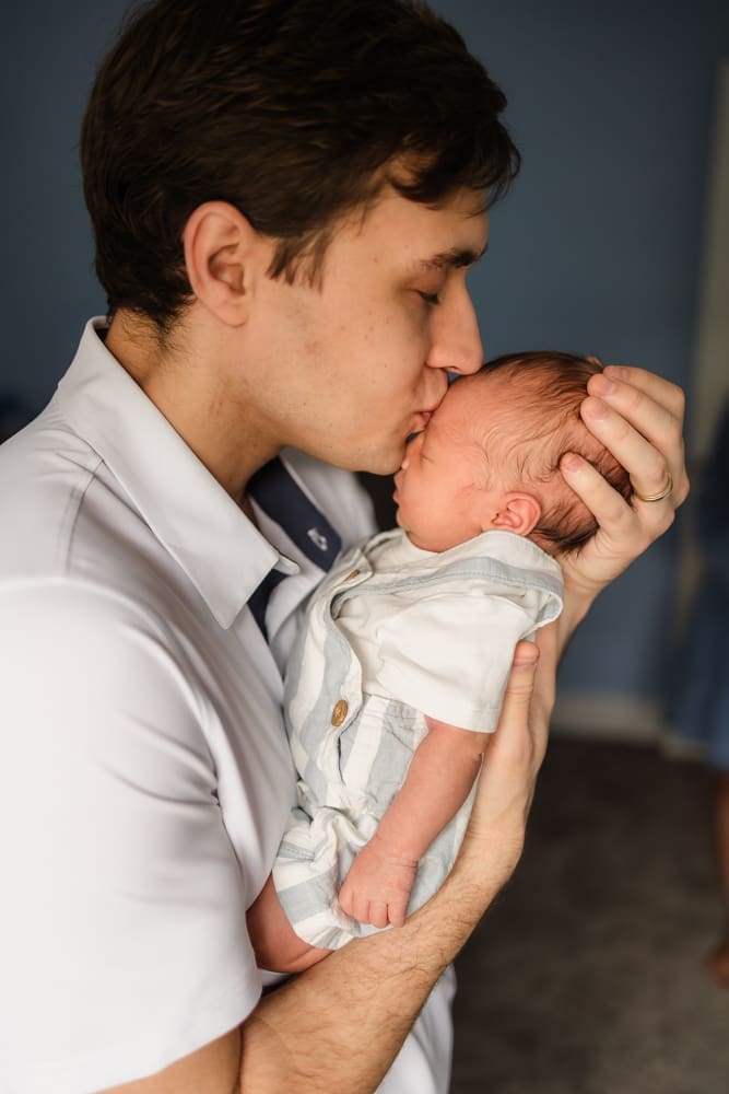 dad kissing newborn boy during knoxville in-home lifestyle newborn photography session