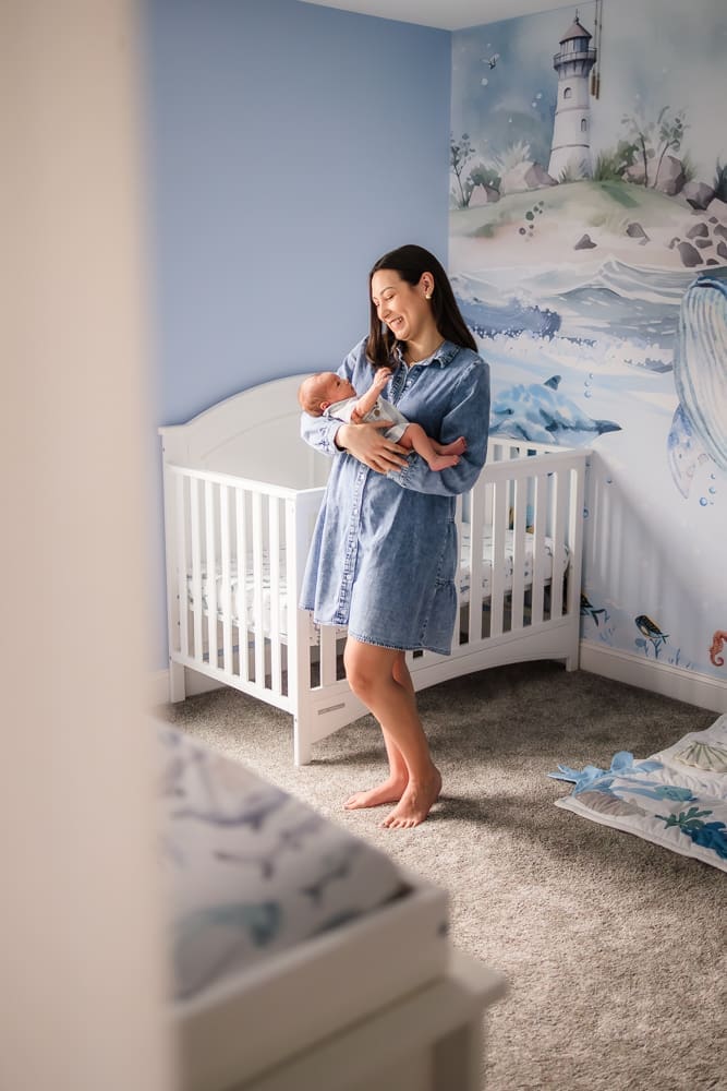 mom holding and admiring newborn baby during knoxville in-home lifestyle newborn photography session
