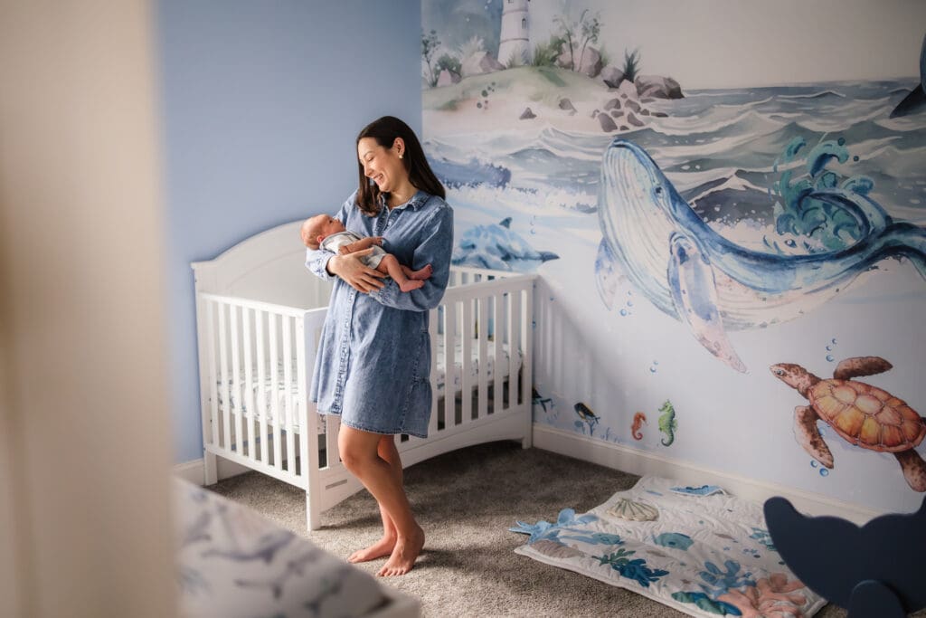 mom admiring baby boy in ocean themed nursery during knoxville in-home lifestyle newborn photography session