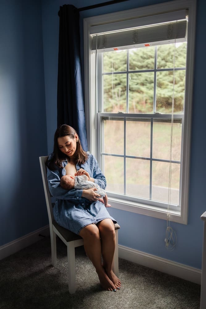 mom sitting nursing during knoxville in-home lifestyle newborn photography session