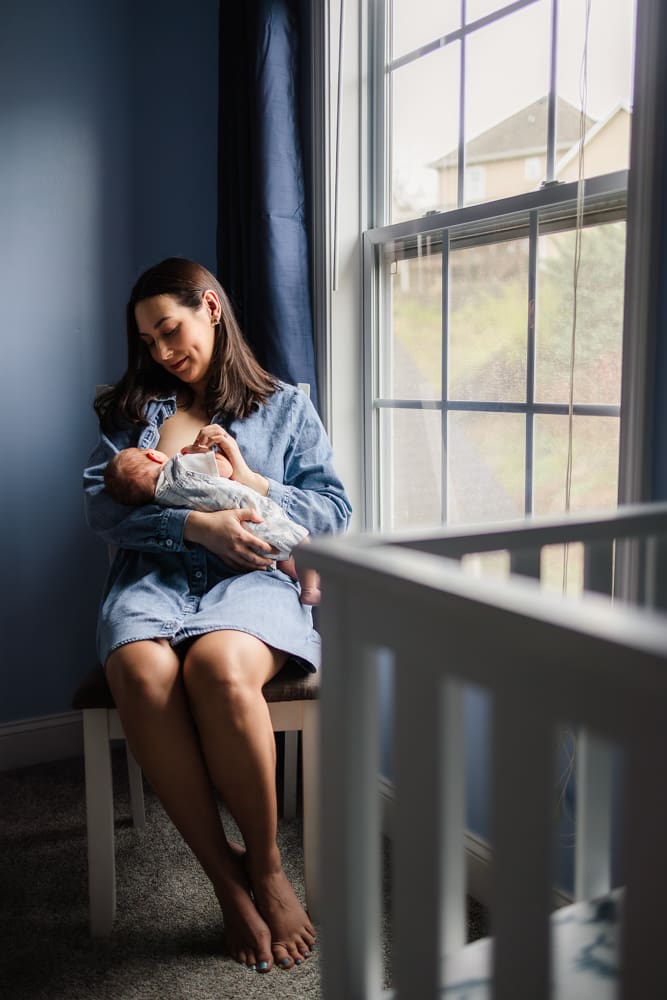 mom smiling at nursing baby during knoxville in-home lifestyle newborn photography session