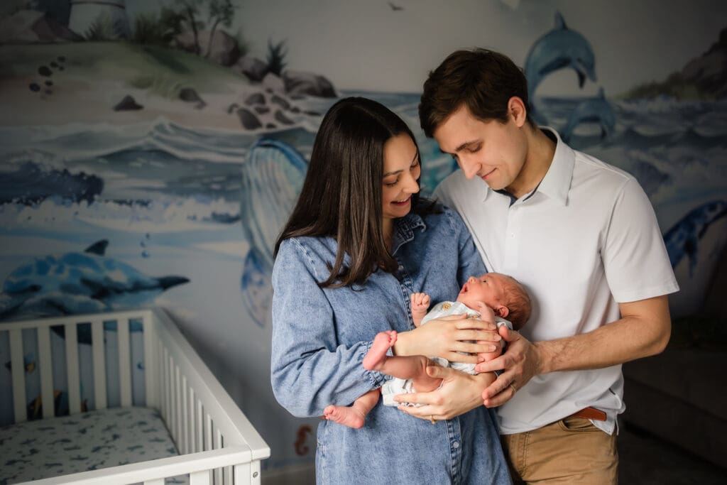 mom and dad looking down at newborn during knoxville in-home lifestyle newborn photography session