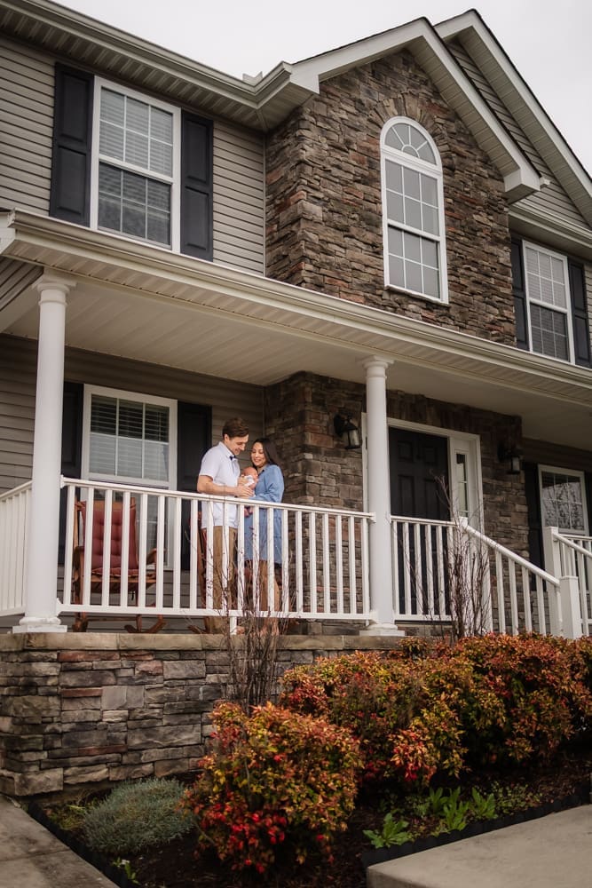 mom and dad welcome newborn to their home on the front porch during knoxville in-home lifestyle newborn photography session