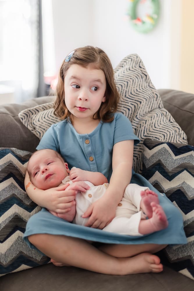 older sister holds her newborn baby brother during knoxville lifestyle newborn portrait session