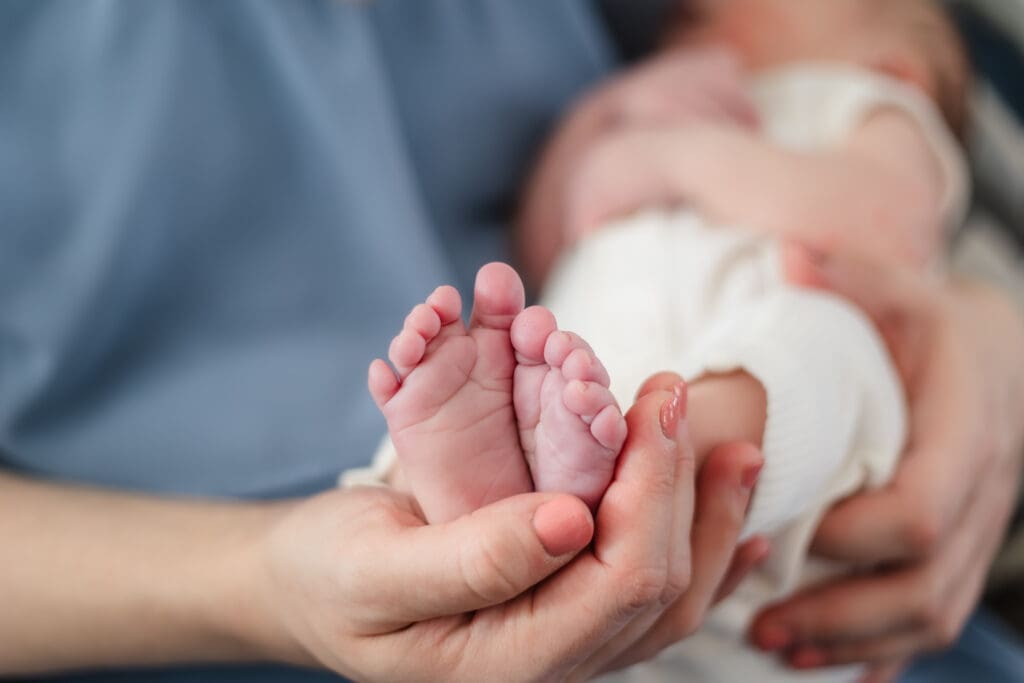 mom cups baby's feet in her hand during west knoxville newborn session in-home lifestyle