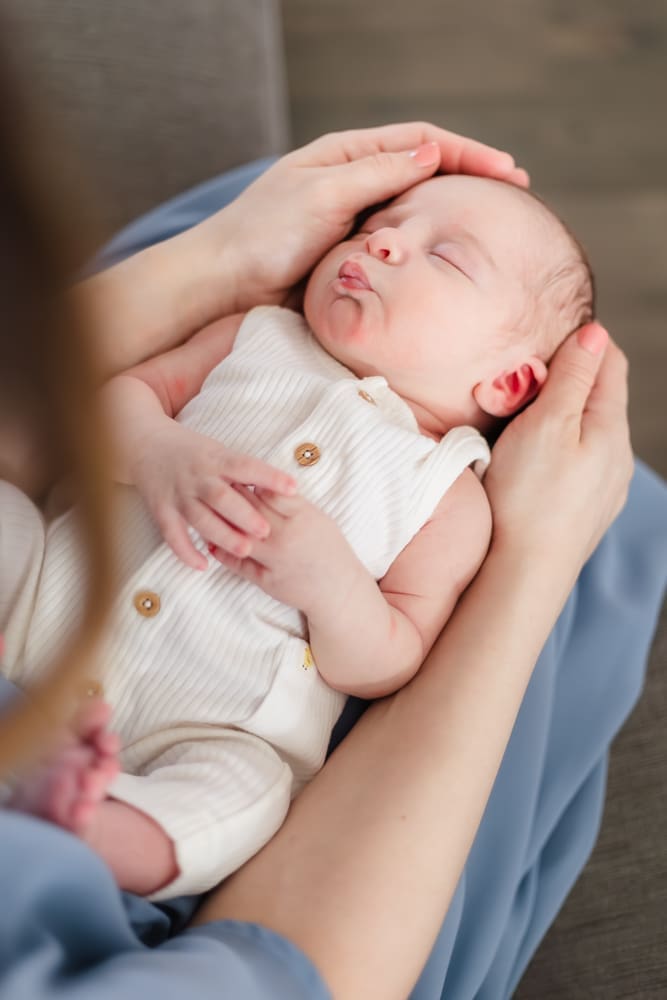 newborn baby boy lays on moms lap and makes funny face during newborn session
