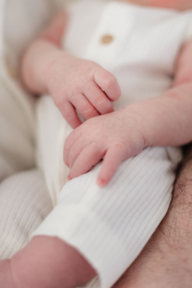 baby's fingers rest on torso during lifestyle newborn photography session