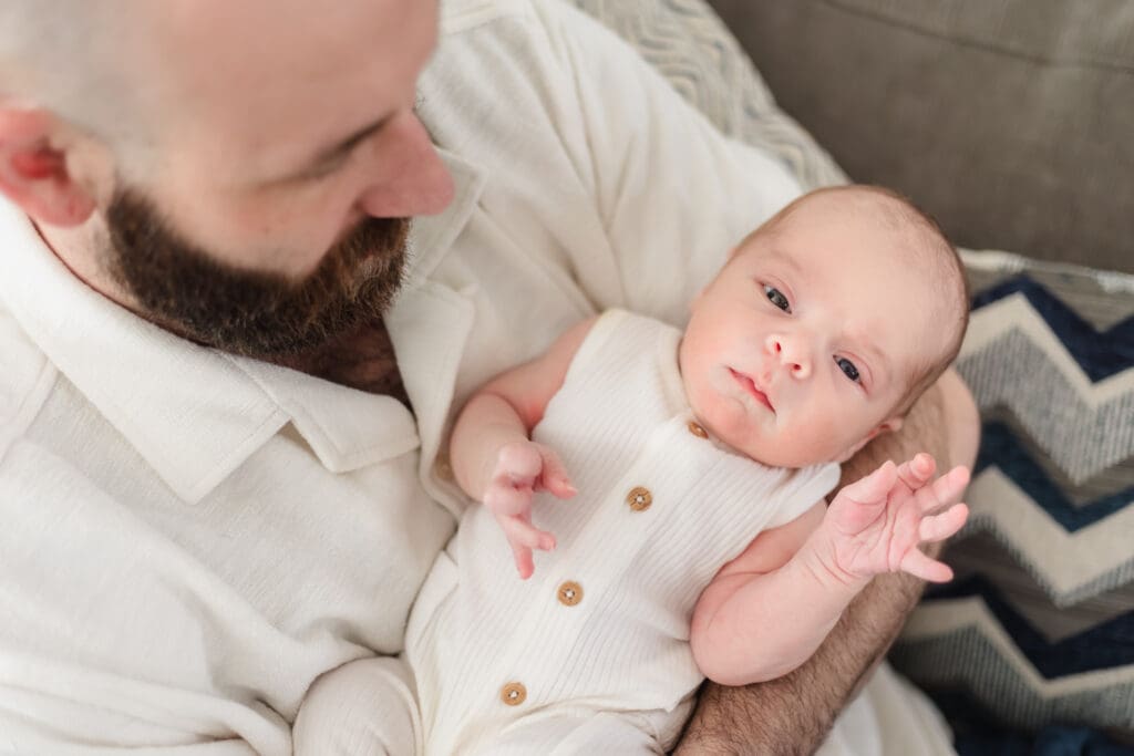 newborn boy waves for camera during lifestyle newborn photography session in-home