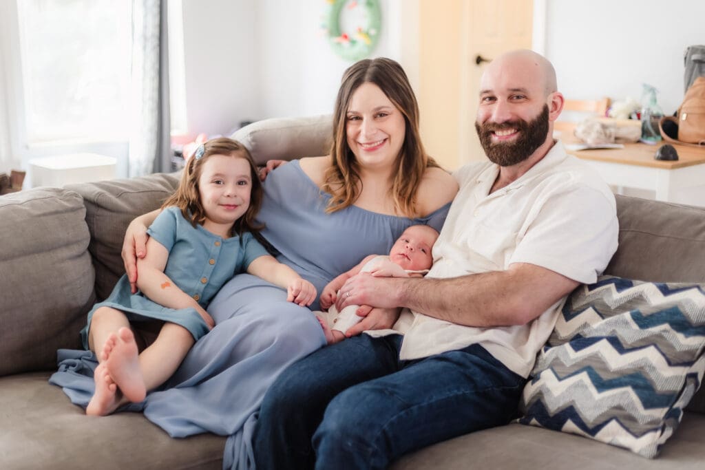 family smiles on couch during newborn session