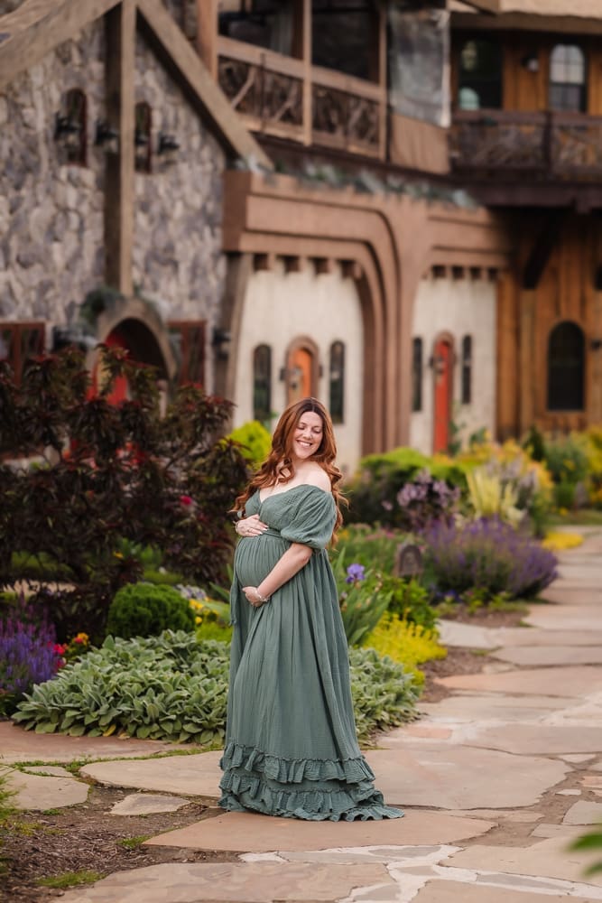 mom holding baby bump in front of cottages during fantasy inspired knoxville maternity photography session at ancient lore village