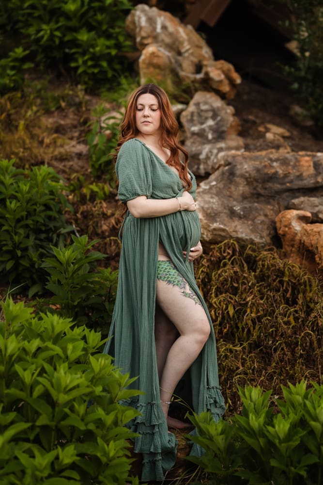 mom standing in greenery during fantasy inspired knoxville maternity photography session at ancient lore village